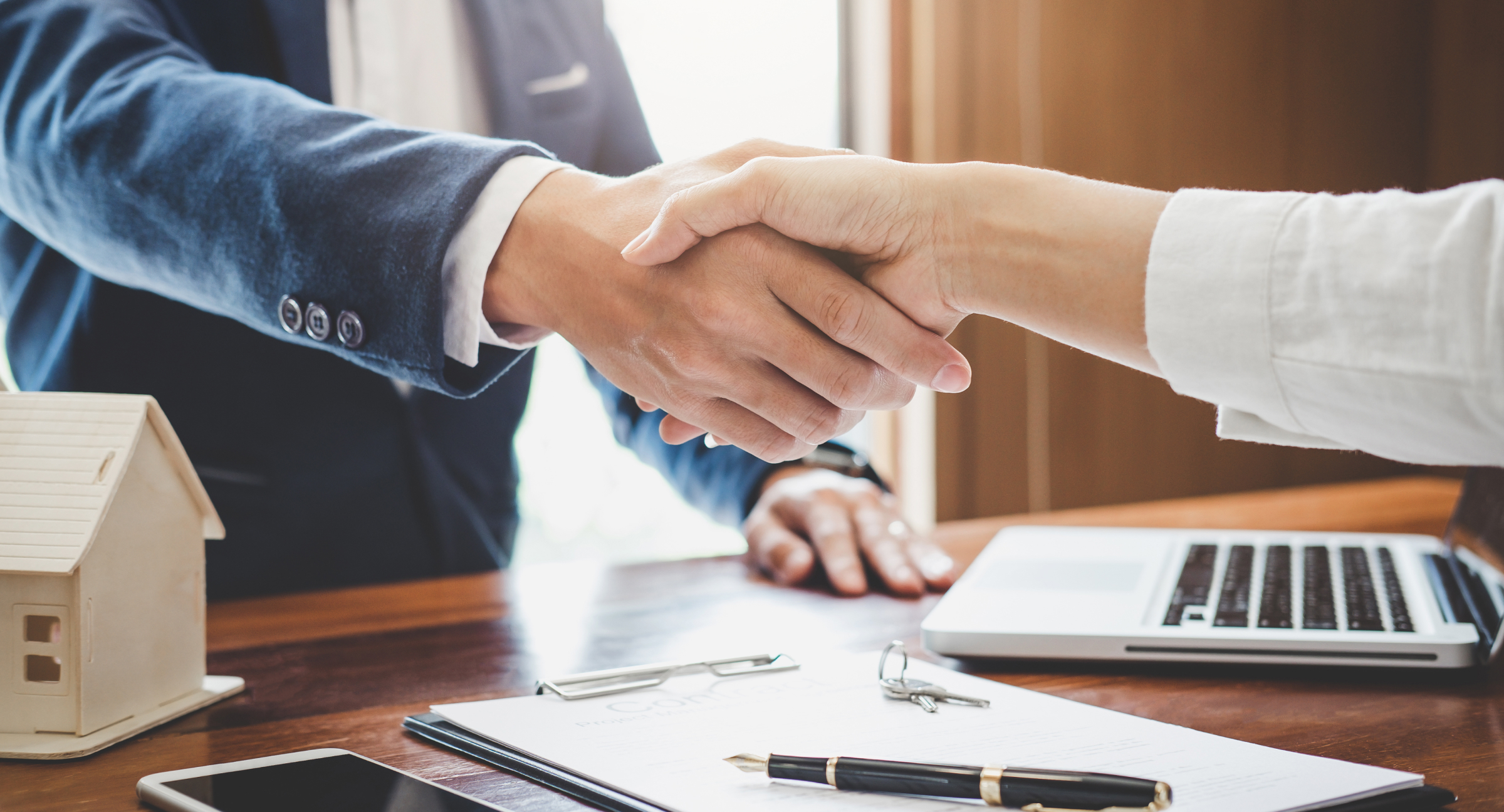 Two people shaking hands across a desk | Tips For Negotiating a Commercial Lease